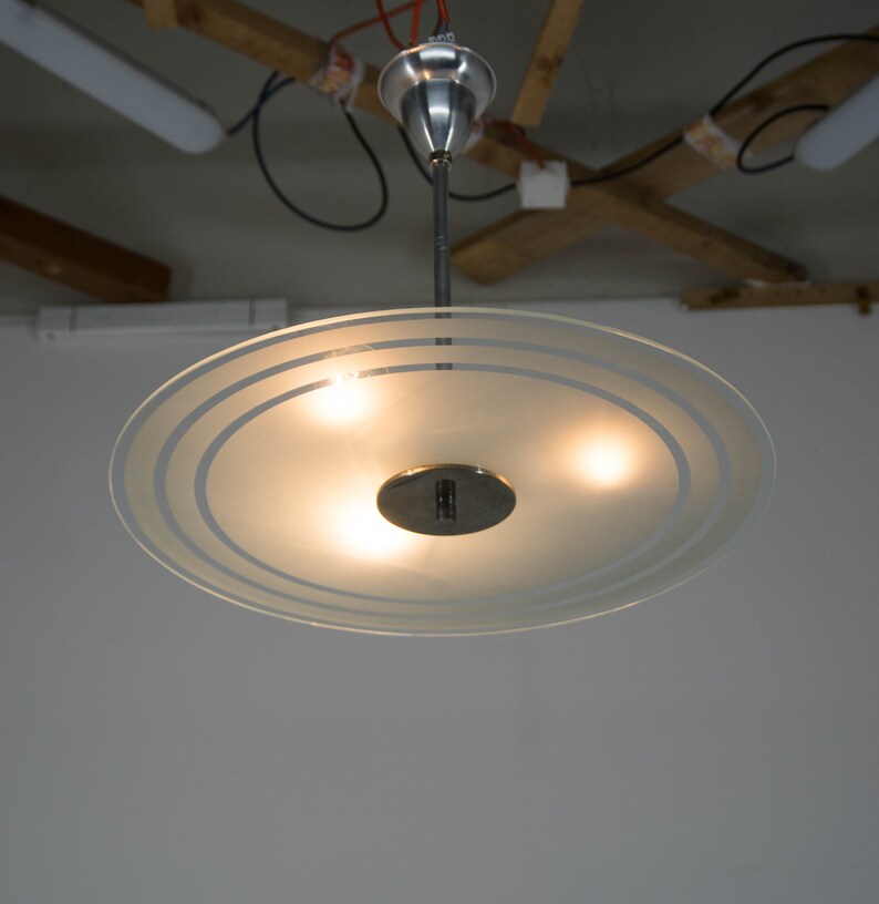 May include: A frosted glass ceiling light fixture with three light bulbs and a silver metal base.