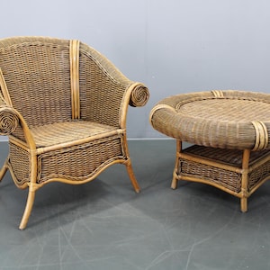 Könnte beinhalten: Ein Vintage-Set aus Korbsessel und Beistelltisch. Der Sessel hat eine hohe Rückenlehne und gerollte Armlehnen. Der runde Beistelltisch hat eine gewebte Oberseite und ein unteres Regal. Beide Teile sind aus hellbraunem Korbgeflecht.