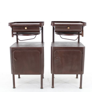May include: Two brown metal bedside tables with a single drawer and a small shelf above the drawer. Each table has a cabinet door with a handle.