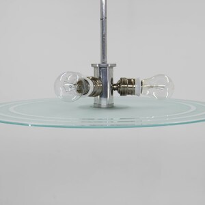 May include: A modern ceiling light fitting with a circular glass shade and two exposed light bulbs.
