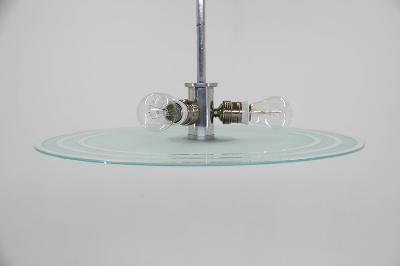 May include: A modern ceiling light fitting with a circular glass shade and two exposed light bulbs.