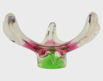May include: A clear glass decorative bowl with a unique shape. The bowl features a vibrant colour scheme, with a base of green, transitioning to a pink hue in the centre, and clear, curved edges.