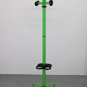 以下が含まれることがあります： 円形のベースと複数のフックが付いた、明るい緑色の金属製コートラック。ラックは、上部にフック、下部にフックのリングが付いた中央のポールを備えています。フックは黒色です。