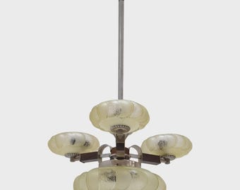 May include: An antique chandelier with a central rod and four frosted glass shades. The shades are a soft yellow color and have a textured, floral-like design. The metal components are silver and dark brown.