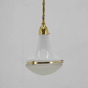 Op de afbeelding: Een witte glazen hanglamp met een messing ketting en een messing rand rond de onderkant van de kap.
