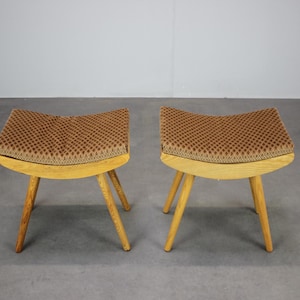 Op de afbeelding: Een paar krukken met gebogen houten frames en gestoffeerde zittingen met een bruin en beige ruitpatroon. Elke kruk staat op vier taps toelopende houten poten, wat een stabiele basis vormt voor de gecapitonneerde, licht holle zitting.