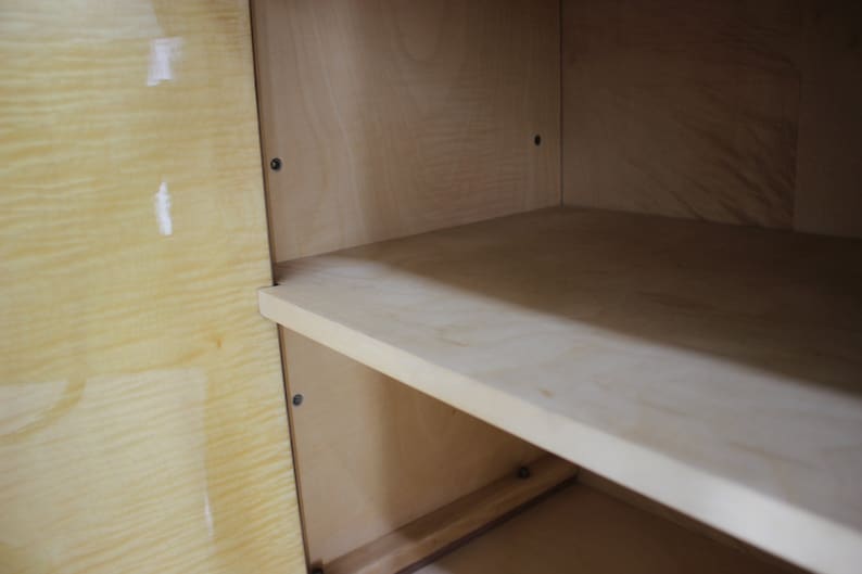 May include: Inside view of a wooden cabinet with a light wood finish. The cabinet has one shelf and is empty.