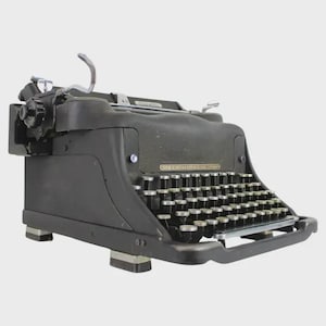 May include: A vintage black typewriter with silver keys and a curved paper holder. The typewriter has a classic design with a keyboard and a carriage return lever. The keys are arranged in a QWERTY layout.