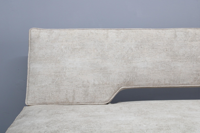 May include: A white fabric sofa with a curved back and a light gray fabric upholstery.