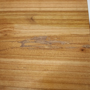 May include: Close-up of a light brown wooden surface with a small crack in the wood.