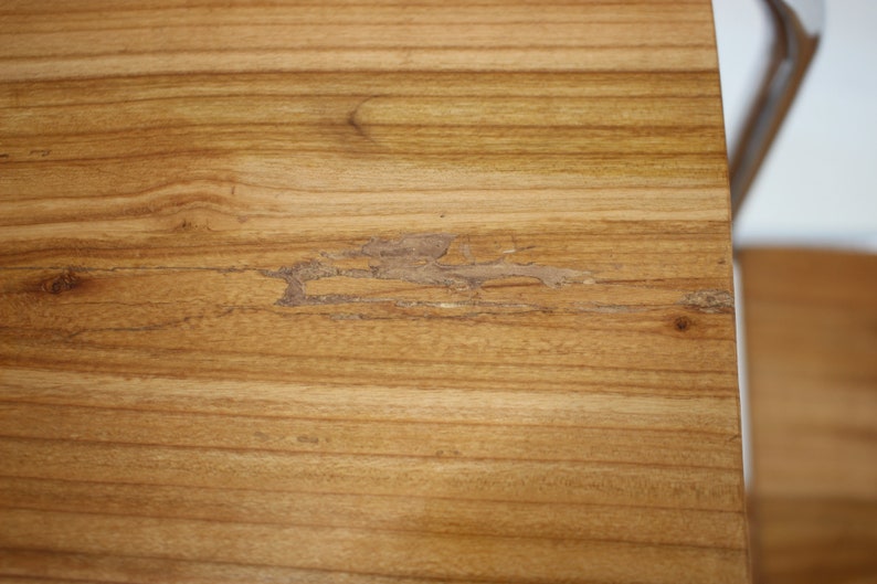 May include: Close-up of a light brown wooden surface with a small crack in the wood.