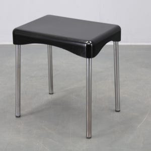 Könnte beinhalten: Ein schwarzer Hocker mit rechteckiger Sitzfläche und geschwungenen Kanten. Er hat vier silberne Metallbeine. Der Hocker ist ein modernes Design, geeignet zum Sitzen oder als Beistelltisch. Die Höhe beträgt ca. 45 cm.