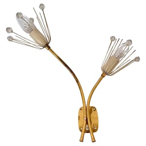 Op de afbeelding: Een vintage wandlamp met een bloemenontwerp. De lamp heeft twee armaturen met heldere lampen, omgeven door dunne, witte metalen staven en kristalachtige accenten. De gebogen armen en de montageplaat zijn goudkleurig.