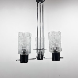 Pode incluir: Um candeeiro de teto de três luzes em cromo e preto com cúpulas de vidro transparente com um padrão geométrico.