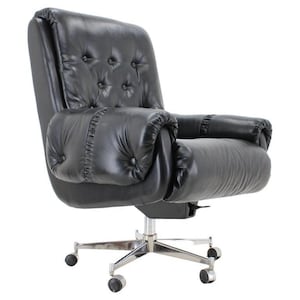 May include: Black leather office chair with a tufted back and armrests. The chair has a chrome base with five wheels. The chair's design is classic and comfortable, suitable for a home or office setting.