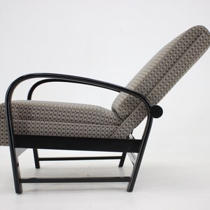 May include: A black reclining chair with a patterned fabric upholstery. The chair has a curved wooden frame and a high back.