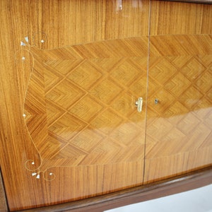 May include: A vintage wooden cabinet with two doors. The doors are made of wood with a diamond pattern and have a brass handle. The cabinet has a curved bottom and is decorated with a floral design.