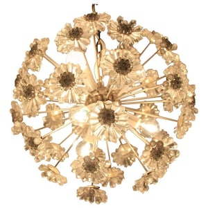May include: A vintage chandelier with a spherical design, featuring numerous clear, flower-shaped glass elements. The fixture has a metallic frame and visible light bulbs, creating a warm, inviting glow. The overall aesthetic is elegant and decorative.