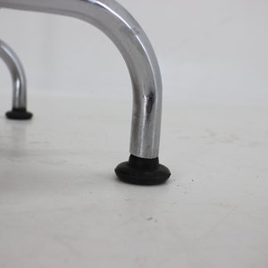 May include: Close-up of the chrome legs of a chair with black rubber feet.
