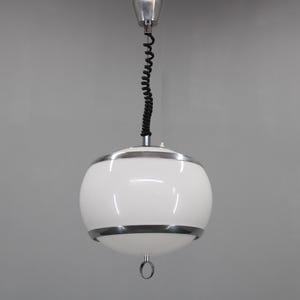Może przedstawiać: Biała lampa wisząca w kształcie kuli ze srebrnym metalowym wykończeniem i czarnym przewodem. Oprawa jest zawieszona na srebrnym uchwycie sufitowym. Kula ma okrągły metalowy pierścień na dole.