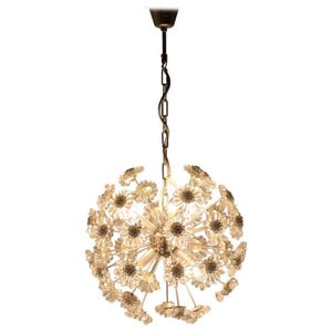 May include: A spherical chandelier with a multitude of clear, flower-shaped glass elements. The fixture hangs from a chain and a canopy, with a central light source. The design is reminiscent of a dandelion, offering a unique lighting solution.