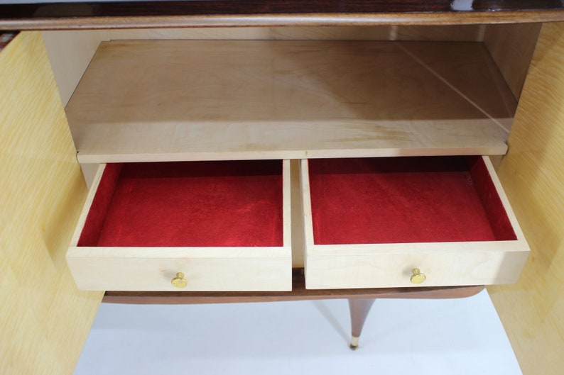 May include: A wooden cabinet with two drawers and a shelf. The drawers are open and lined with red felt. The cabinet has a light wood finish and brass hardware.