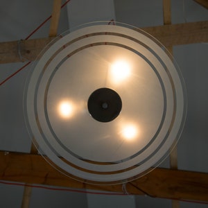 May include: A frosted glass ceiling light fixture with three light bulbs and a black centre piece.
