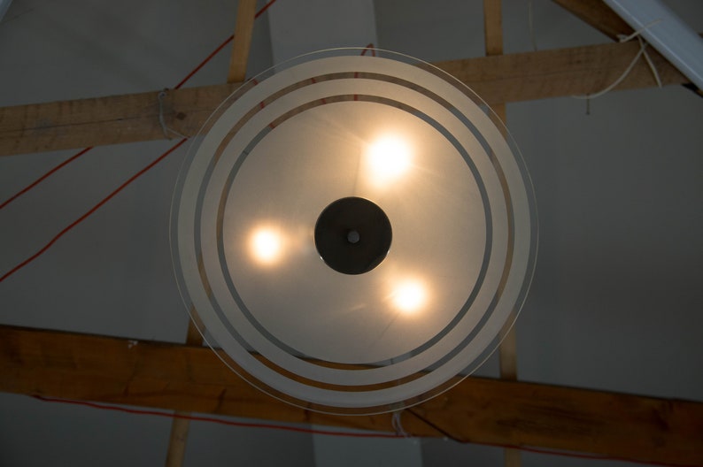 May include: A frosted glass ceiling light fixture with three light bulbs and a black centre piece.