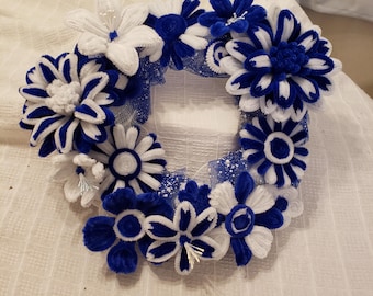 May include: A blue and white wreath made of pipe cleaners, decorated with flowers. The wreath is made of blue and white pipe cleaners and is decorated with blue and white flowers.