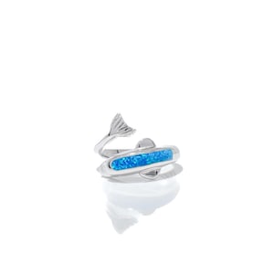 May include: A silver ring featuring a blue opal inlay and a dolphin tail design.