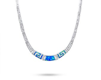 May include: A silver-toned necklace with a Greek key design. The necklace features a curved central section with a vibrant blue opal stone. The opal is surrounded by a silver setting, and the chain has a repeating geometric pattern.