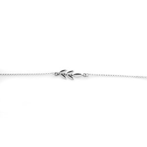 Puede incluir: Un brazalete delicado de cadena de plata con un pequeño encanto de rama de olivo estilizado.