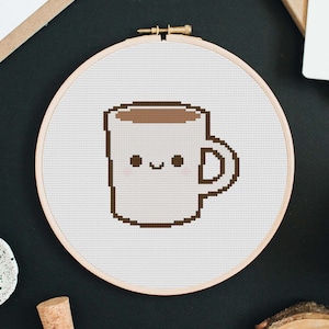 May include: A white coffee mug with a brown rim and brown coffee inside. The mug has a cute cartoon face with two black eyes and a smile.