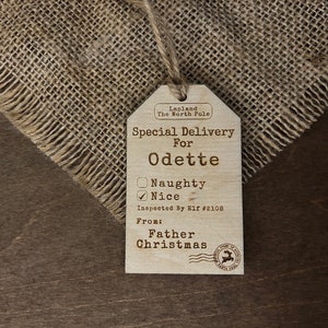 May include: A wooden Christmas gift tag with the text "Special Delivery for Odette" and a checkbox marked "Nice". The tag is from "Father Christmas" and is from Lapland, the North Pole.
