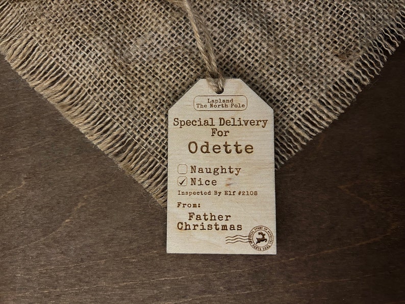 May include: A wooden Christmas gift tag with the text "Special Delivery for Odette" and a checkbox marked "Nice". The tag is from "Father Christmas" and is from Lapland, the North Pole.