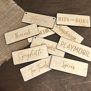 May include: A collection of wooden labels with various text, including "Gluten Free", "Bits and Bobs", "Thread", "Spaghetti", "Playmobil", "Spices", and "Tea Towels".
