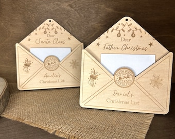 May include: Two wooden Christmas letter envelopes with a North Pole stamp and a slot for a letter. The envelopes are decorated with Christmas lights, stars, and snowflakes. One envelope says "Dear Santa Claus" and the other says "Dear Father Christmas".