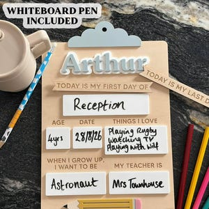 May include: A wooden school milestone board with a light blue cloud-shaped top. The board features the name Arthur, sections for age, date, things I love, and future career goals. It includes white dry-erase panels and a pencil graphic. Whiteboard pen included.