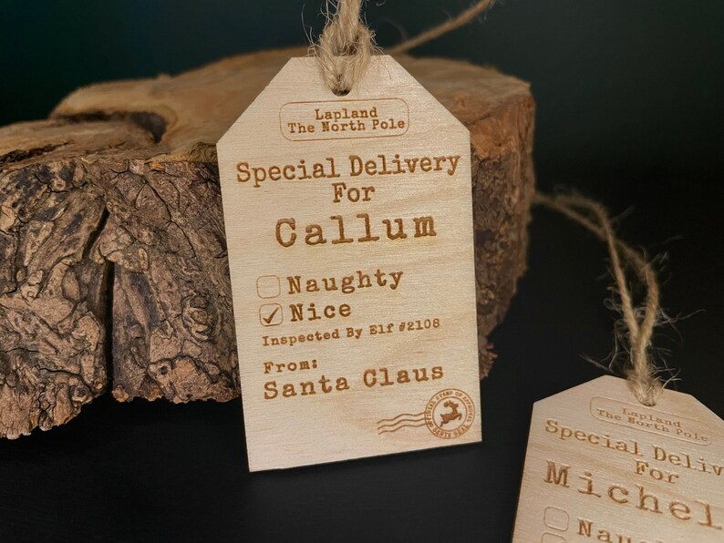 May include: A wooden Christmas gift tag with the text "Special Delivery for Callum" and a checkbox marked "Nice". The tag is decorated with a stamp that says "Lapland The North Pole" and "From: Santa Claus".