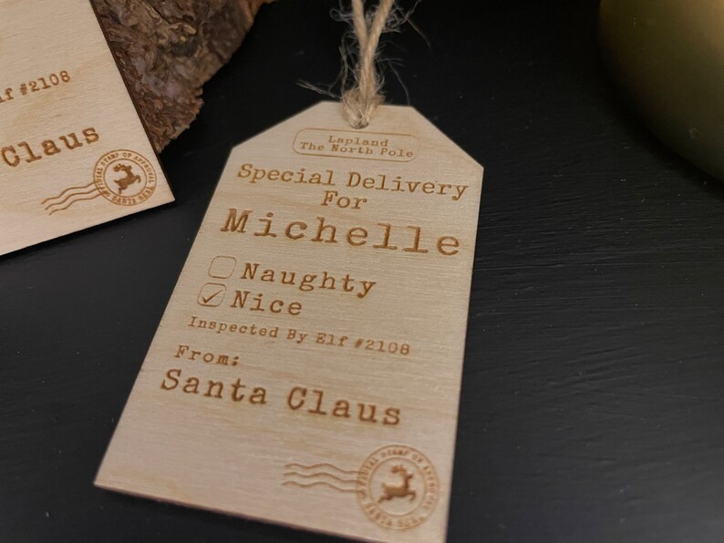 May include: A wooden Christmas gift tag with the text "Special Delivery for Michelle" and a checkbox marked "Nice". The tag also includes the text "Inspected By Elf #2108" and "From: Santa Claus".