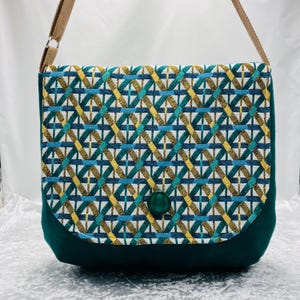 Peut inclure: Sac bandoulière rectangulaire avec un motif géométrique en bleu sarcelle, or et blanc. Le rabat et la base sont vert foncé uni, avec une fermeture à bouton vert assorti. La bandoulière réglable est marron clair.