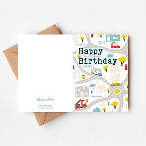 Może przedstawiać: Kartka urodzinowa z kolorową sceną miejską, przedstawiającą drogi, budynki, drzewa i pojazdy. Na kartce widnieje napis "Happy Birthday" czarnymi literami. W zestawie z brązową kopertą.