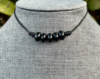 May include: A black leather choker necklace with five black round beads.