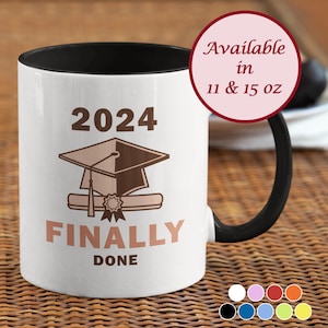 May include: White ceramic coffee mug with a black handle and black interior. The mug has a brown graduation cap and diploma design with the text "2024 FINALLY DONE". Available in 11 and 15 oz.