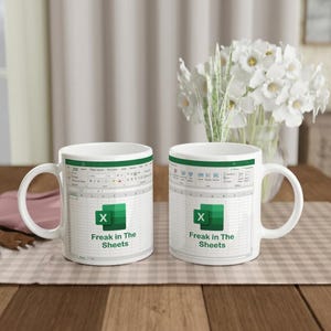 May include: Two white ceramic mugs featuring a printed graphic of a Microsoft Excel spreadsheet interface. The design includes the green Excel logo and the black text "Freak in The Sheets" centered on the front of each mug with a handle.