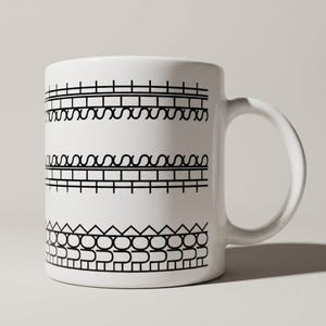 Może przedstawiać: Biały ceramiczny kubek z czarnym nadrukiem graficznym składającym się z trzech poziomych pasów. Górny i środkowy pas przedstawiają powtarzające się geometryczne linie i wzory fal, natomiast dolny pas zawiera rząd trójkątów, kół i kwadratów.