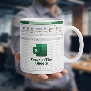 May include: A white ceramic mug featuring a printed graphic of a spreadsheet interface. The design includes the Microsoft Excel logo and the text "Freak in The Sheets" centered over a grid of cells, with a toolbar visible at the top of the mug.