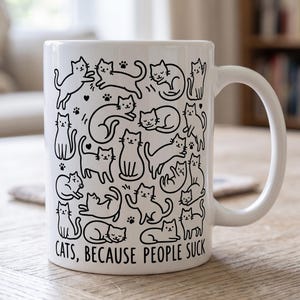 May include: A white ceramic mug featuring a repeating black line art pattern of various cats in different poses, including sitting, stretching, and sleeping, interspersed with small paw prints. The text "CATS, BECAUSE PEOPLE SUCK" is printed in black.