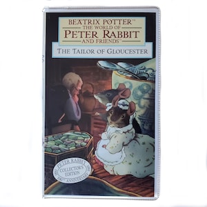May include: A VHS tape of The Tailor of Gloucester from The World of Peter Rabbit and Friends series. The cover features an illustration of a tailor and two mice in period clothing, with a 100th Anniversary Collector's Edition seal at the bottom.