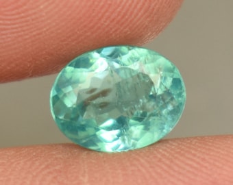 May include: A light green oval-shaped gemstone with a faceted cut.
